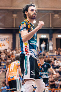 foto piano americano del capitano Filippo Agostini della prima squadra della Scuola Pallavolo Biellese esulta durante i playoff a Biella, sullo sfondo giocatori e tifo sugli spalti