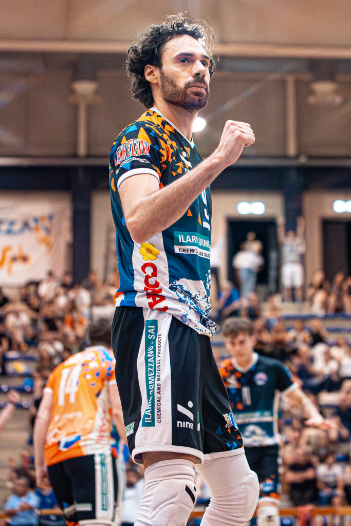 foto piano americano del capitano Filippo Agostini della prima squadra della Scuola Pallavolo Biellese esulta durante i playoff a Biella, sullo sfondo giocatori e tifo sugli spalti