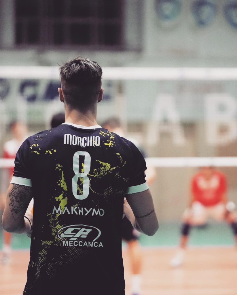 pallavolista in divisa di spalle in campo da pallavolo con maglia scura e numero 8